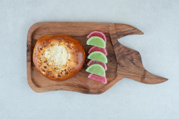 A wooden cutting board with round pastry and jelly candy .