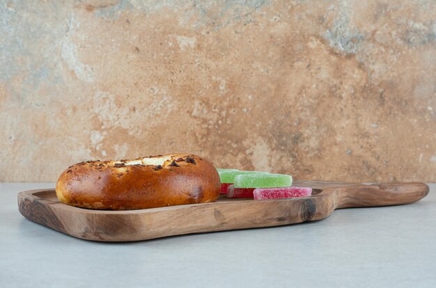 A wooden cutting board with round pastry and jelly candy .