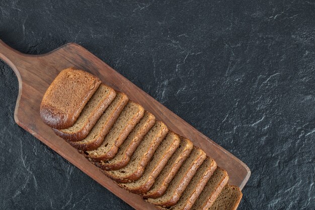 Деревянная разделочная доска с кусочками хлеба.