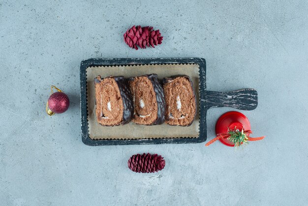 Una tavola di legno scuro con fette di pan di spagna roll con crema.