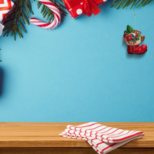 Деревянный стол на синей стене, украшенный рождественскими украшениями