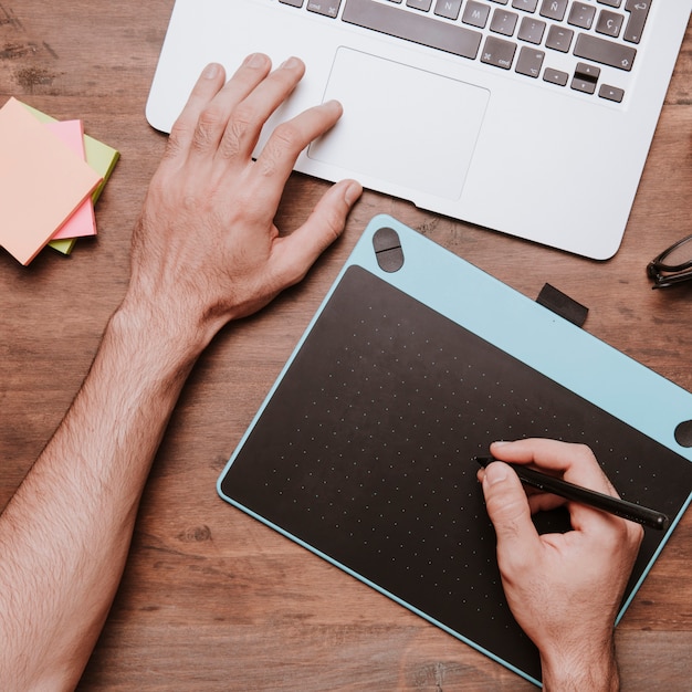 Free photo wooden desk concept with design tablet and hands