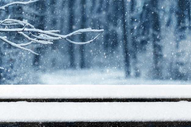 Деревянный стол, покрытый снегом и зимним фоном во время снегопада, свободное место для вашего украшения. зимний фон с метелью