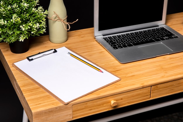 Wooden desk with clipboard and laptop
