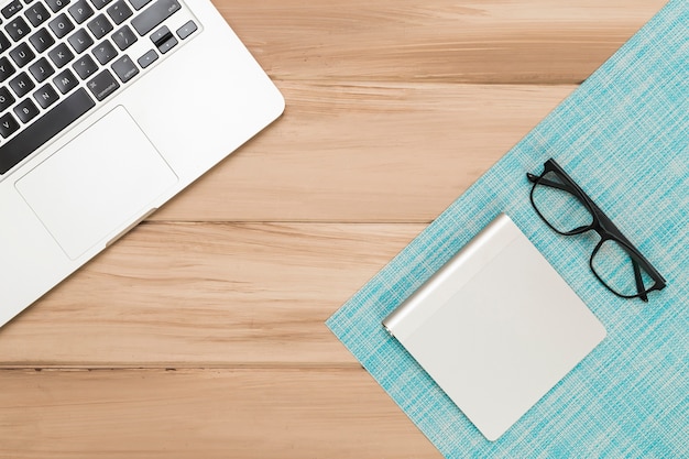 Wooden desk with laptop and eyeglasses 