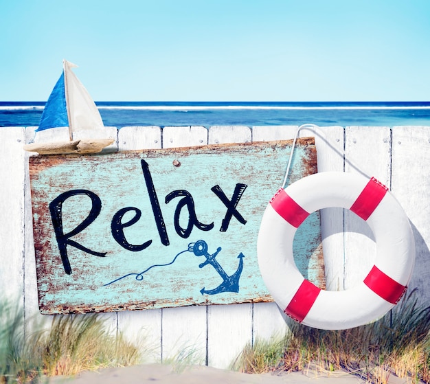 Free photo wooden fence and relax sign board on beach