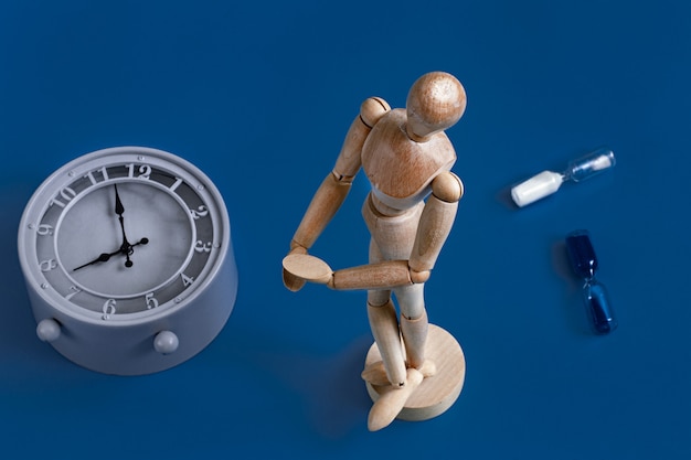 Free photo wooden figure of a man on blue with a clock