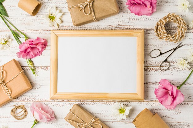 Wooden frame; gifts; pink eustoma flowers and scissor on wooden surface