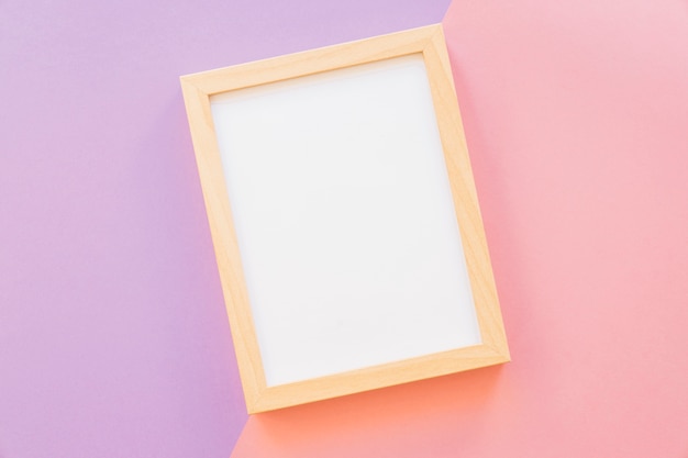 Free photo wooden frame on pink and purple background