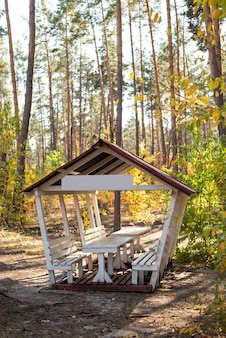 Wooden gazebo with a table and benches for relaxation and picnic on a weekend in nature