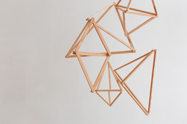 Wooden geometric decor hanging from ceiling isolated on white wall background. 