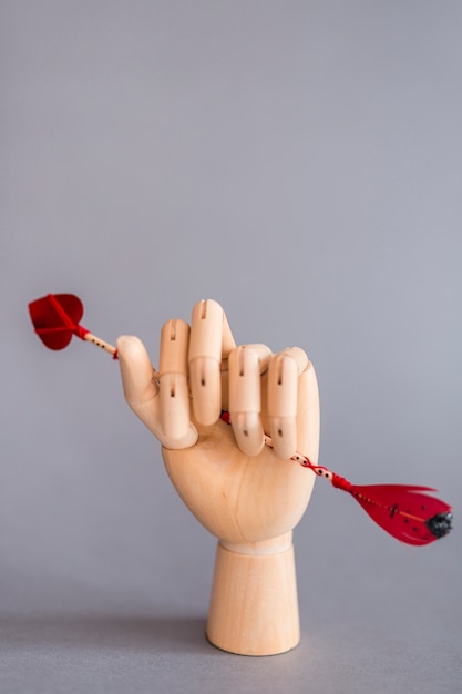 Бесплатное фото Деревянная рука, держащая любовную стрелу на столе