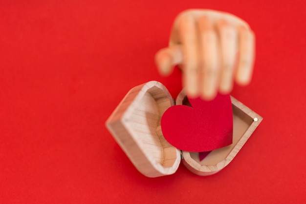 赤い心、赤いテーブルに木製の手