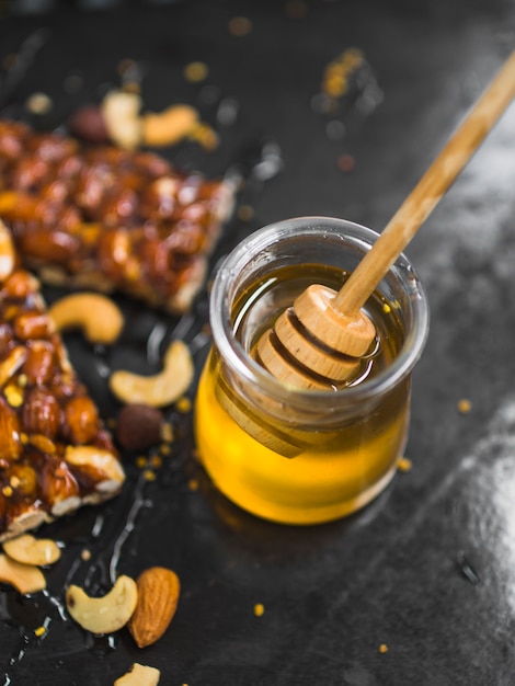 Wooden honey dipper in pot with granola