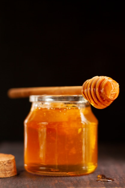 Wooden honey dipper on top of honey jar