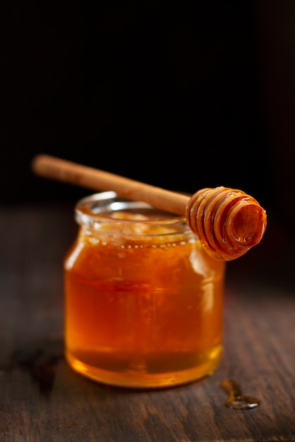 Wooden honey dipper on top of honey jar