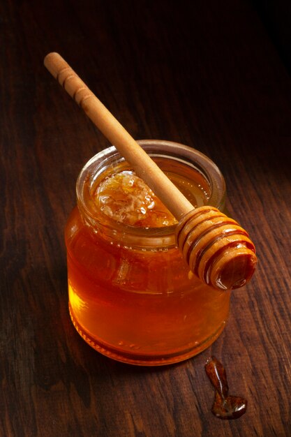 Wooden honey dipper on top of honey jar