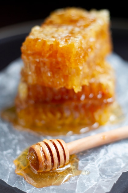 Wooden honey dipper with honeycomb on waxed paper