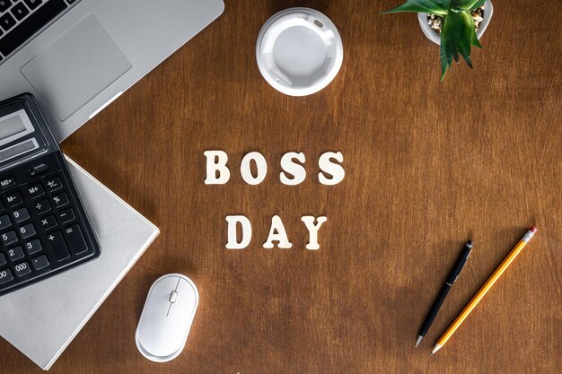 Wooden inscription boss day on a wooden office desk background top view