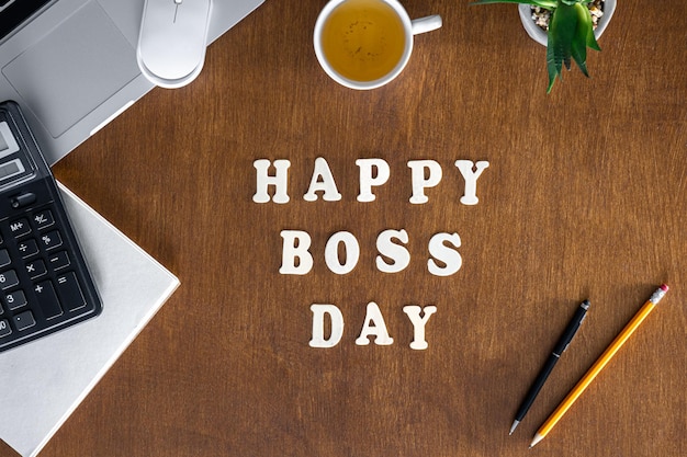 Wooden inscription happy boss day on a wooden office desk background