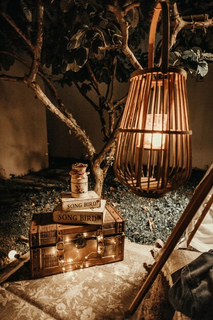 wooden lampshade and a wooden chest with books on it placed in a garden