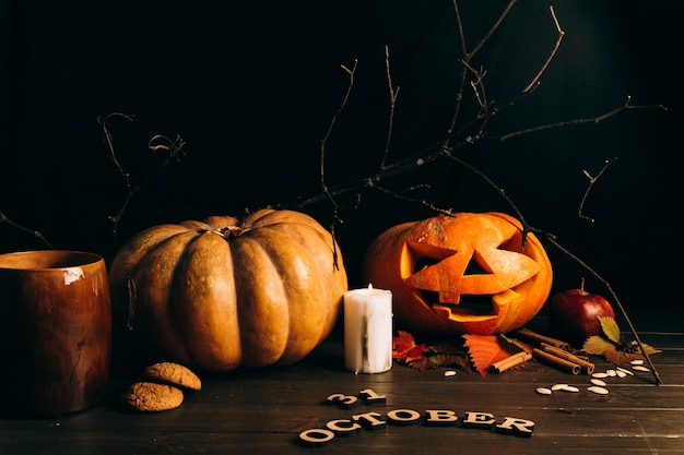 Wooden lettering '31 october' lie before large scarry hallooween pumpkins