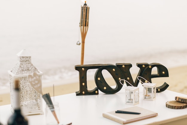 Free photo wooden lettering love stands on dinner table with decorative lanterns