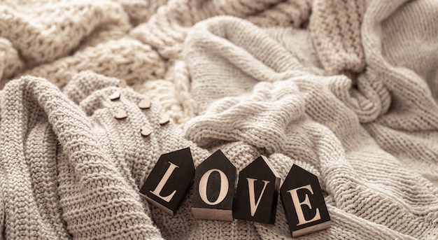 Wooden letters make up the word love on a background of cozy knitted items. 