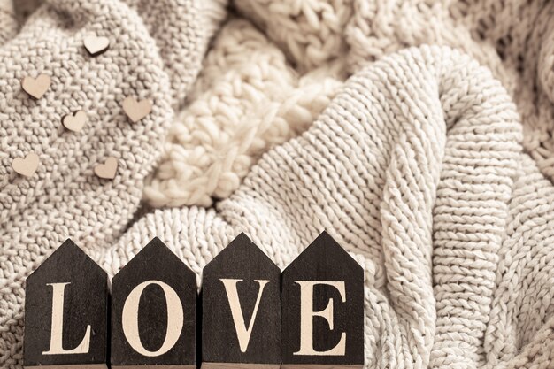 Wooden letters make up the word love on a background of cozy knitted items. 