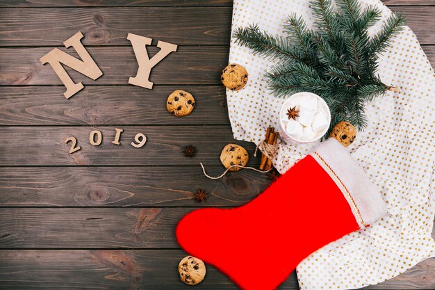 木製の手紙「NY 2018」は、クッキー、モミの枝、ホットチョコレート、暖かい靴下で囲まれた床に置かれています