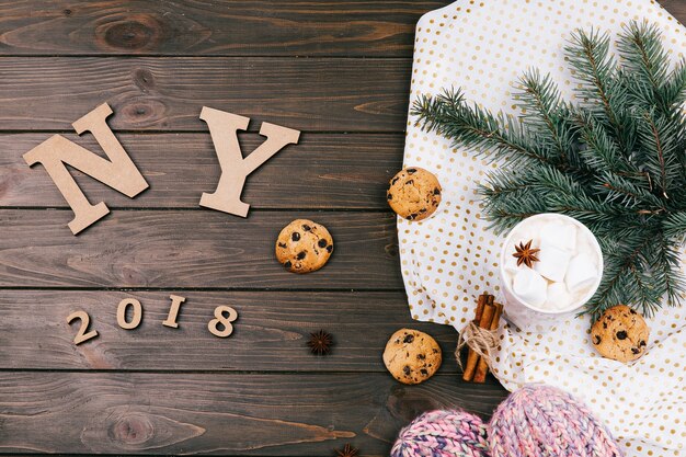 Wooden letters 'NY 2018' lie on the floor surrounded with cookies, fir branches and warm socks