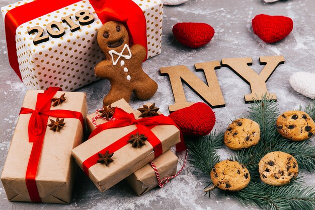 Wooden letters 'NY 2019' lie on the floor surrounded with cookies, fir branches, and present boxes