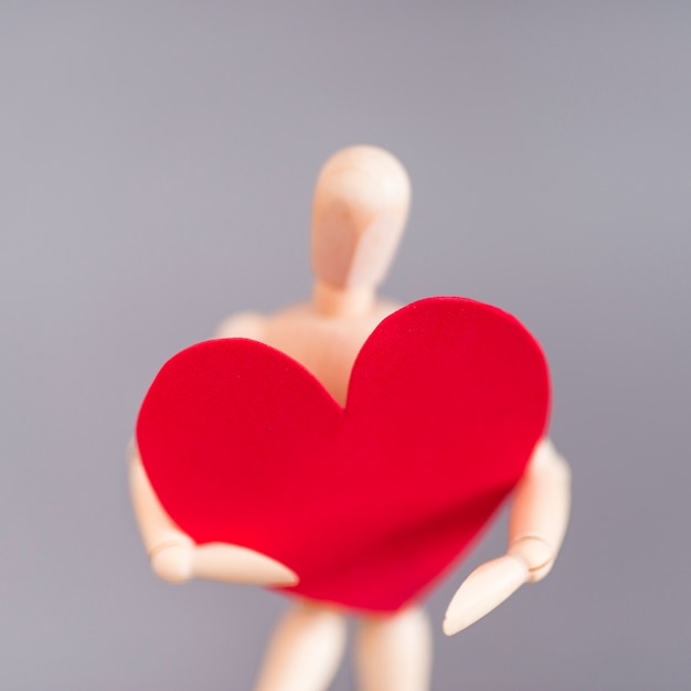 Wooden mannequin holding big red heart