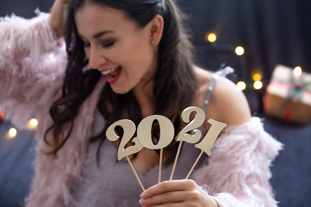 Деревянный номер нового года на фоне девушки с счастливым лицом крупным планом.