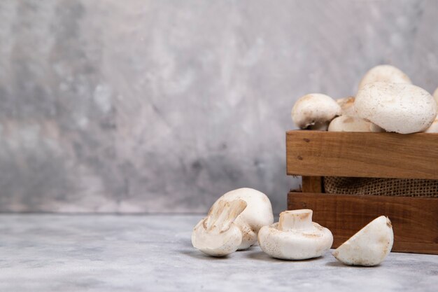 Wooden old box of fresh whole champignon mushrooms isolated on stone