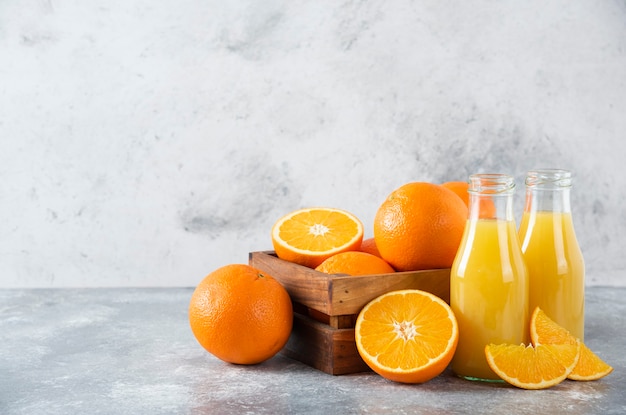 A wooden old box full of juicy orange fruit on stone table .