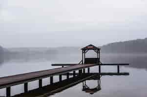 Free photo wooden pathway above the water surrounded by trees with a foggy background