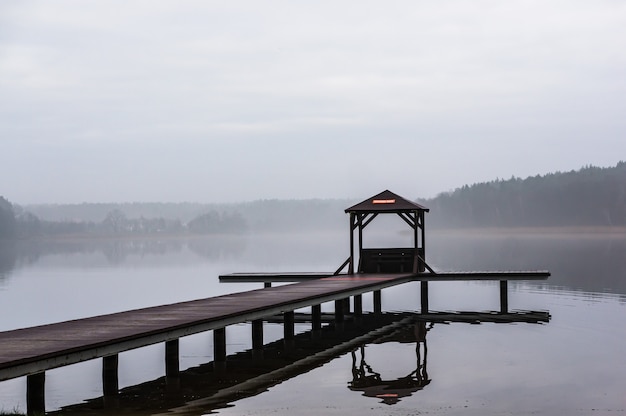 Wooden pathway above the water surrounded by trees with a foggy background