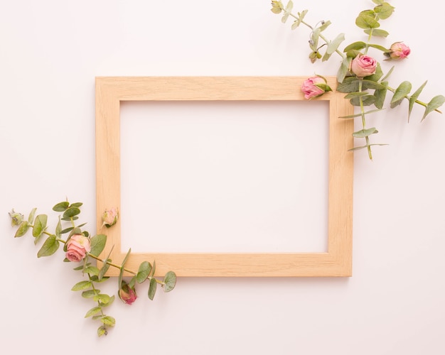 Деревянная рамка для фотографий украшена розовыми розами и эвкалиптом