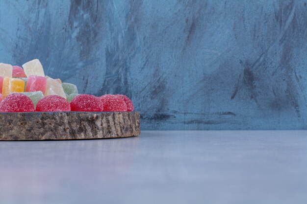 A wooden piece board full of colorful sugary jelly candies. 