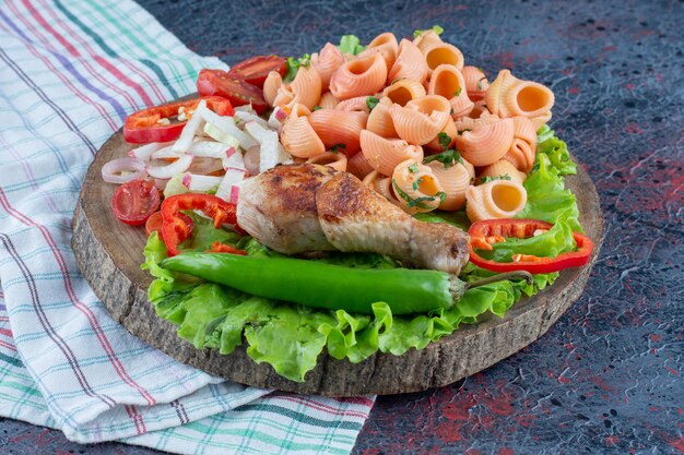 A wooden piece of delicious chicken leg meat with vegetable salad . 