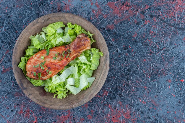 야채 샐러드와 함께 맛있는 닭 다리 고기의 나무 조각
