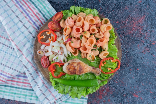 A wooden piece of delicious chicken leg meat with vegetable salad 