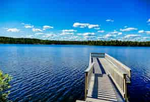 Foto gratuita molo in legno sul bellissimo lago con gli alberi e il cielo blu sullo sfondo in svezia