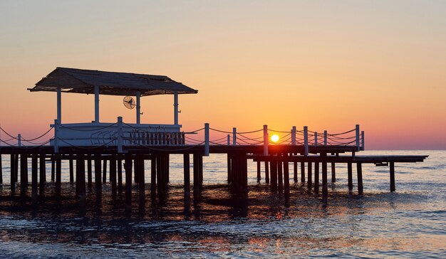 派手なオレンジ色の夕日に木製の桟橋。