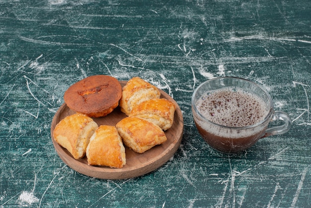 Wooden plate of bakery with hot tea on marble table