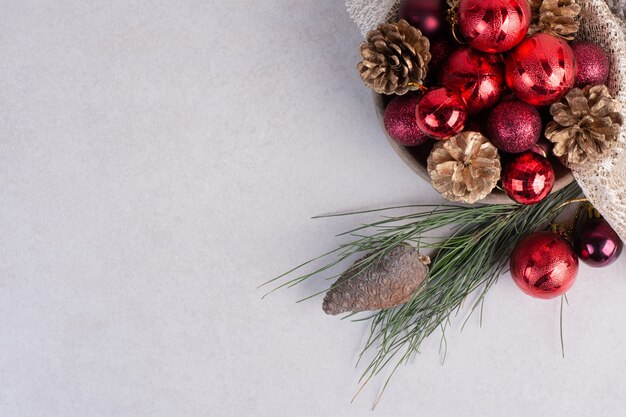 A wooden plate of Christmas red balls and pinecones on burlap