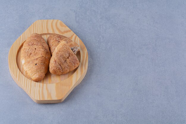 A wooden plate of croissants with delicious chocolate .