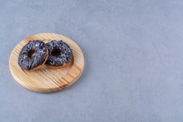 A wooden plate of delicious chocolate doughnuts with sprinkles