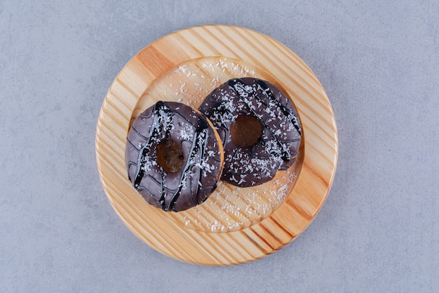 Free photo a wooden plate of delicious chocolate doughnuts with sprinkles